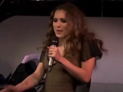 Lily Sastry is performing on stage holding the mic.